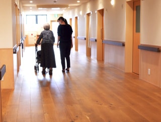 介護・福祉施設内を歩く高齢者と施設関係者